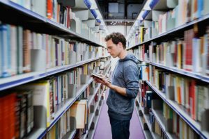 Man looking at shelves in library : 16 things you might not know about early career researchers