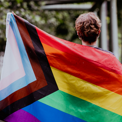 Person holding LGBTQ+ flag